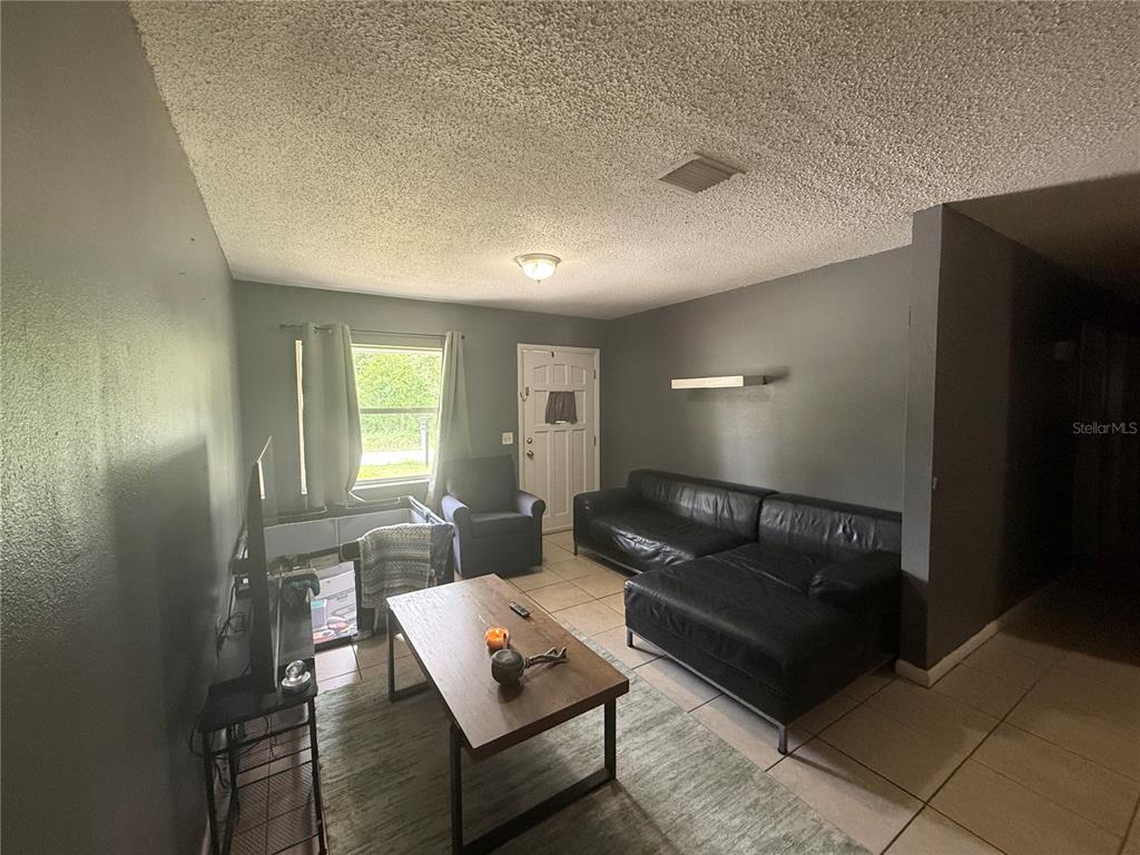 A living room features dark gray walls, tile flooring, a black sectional sofa, and a coffee table — 11129 ROBERTS LANE, RIVERVIEW, FL