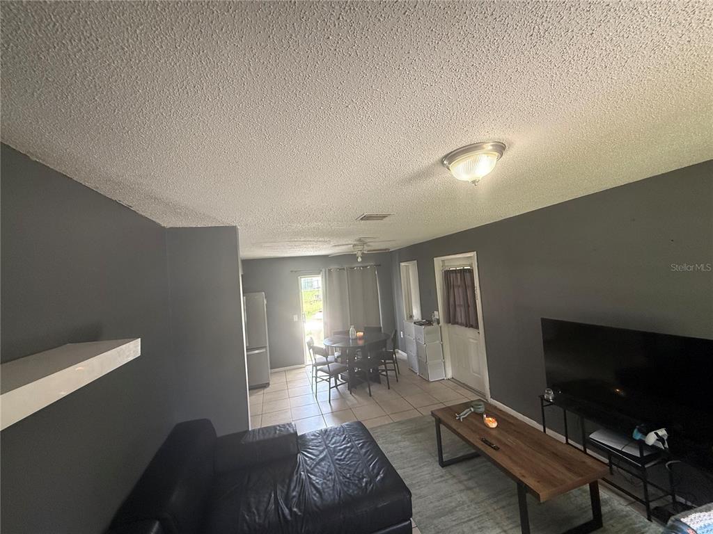 A living room with dark gray walls, a black leather sofa, and a dining area — 11129 ROBERTS LANE, RIVERVIEW, FL
