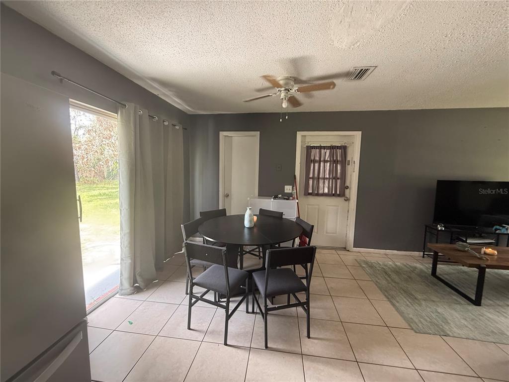 A dining area with a round table and chairs sits next to a sliding glass door — 11129 ROBERTS LANE, RIVERVIEW, FL