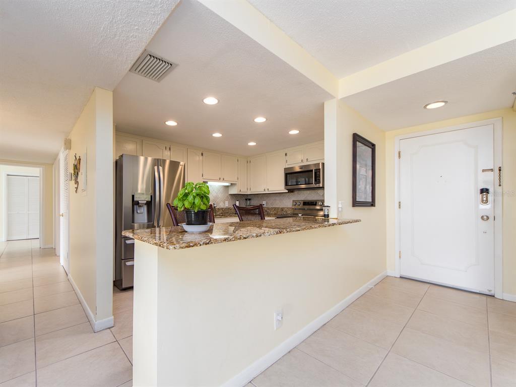 A kitchen with a granite breakfast bar, stainless steel appliances, and light-colored cabinets — 675 S GULFVIEW BOULEVARD UNIT 902, CLEARWATER BEACH, FL