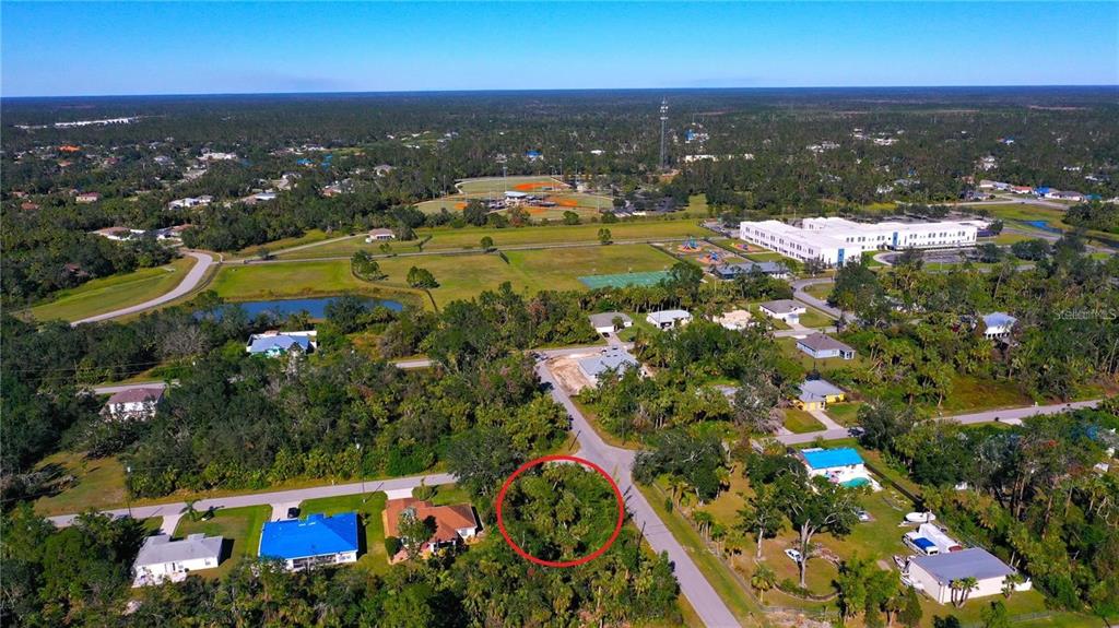 An aerial view shows a vacant, tree-covered lot circled in red within a residential neighborhood — SNYDER   (LOT 6 BLOCK 1019) STREET, NORTH PORT, FL