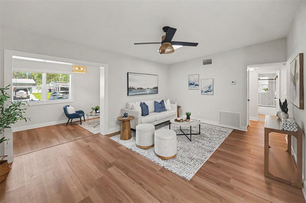 A living room with light wood floors, a white sofa, and an adjacent sunroom area — 340 55TH AVE S, ST PETERSBURG, FL