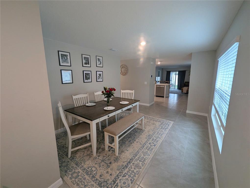 A dining area features a wooden table with chairs and a bench on a rug — 37377 ANGEL WINGS AVENUE, ZEPHYRHILLS, FL
