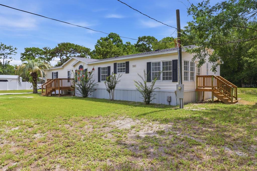 A single-story manufactured home with light siding, black shutters, and two wooden entry decks — 4215 N ASHTON TERRACE, CRYSTAL RIVER, FL