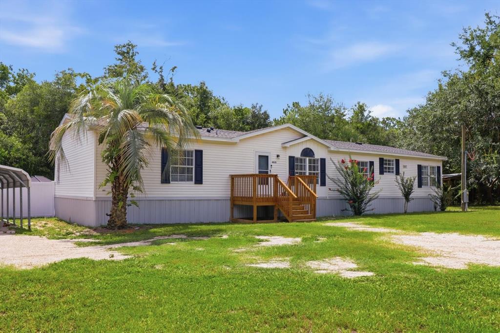 A single-story manufactured home with light siding, dark shutters, and a wooden front deck — 4215 N ASHTON TERRACE, CRYSTAL RIVER, FL
