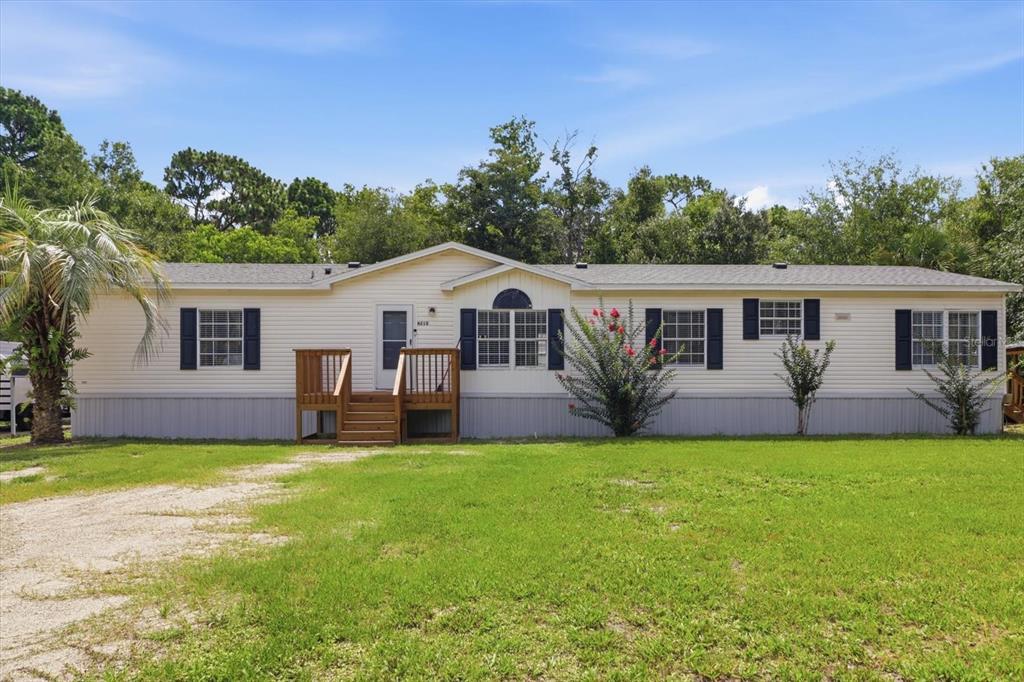 A single-story manufactured home with light siding, dark shutters, and a wooden front porch — 4215 N ASHTON TERRACE, CRYSTAL RIVER, FL