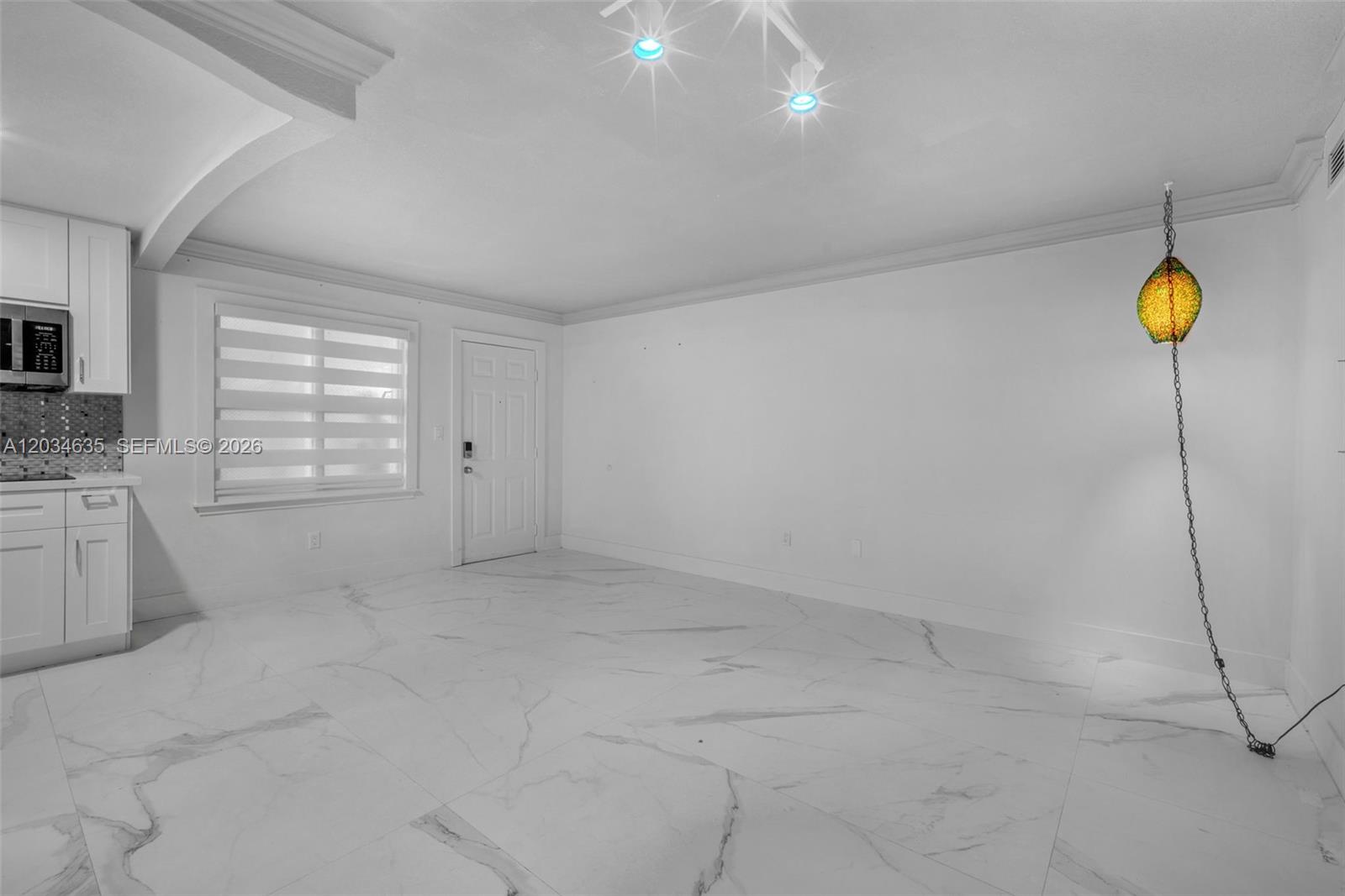 A white room features marble-patterned tile flooring, a kitchen corner, and a hanging yellow lamp — 3245 Virginia St # 16, Miami FL 33133, MIAMI, FL