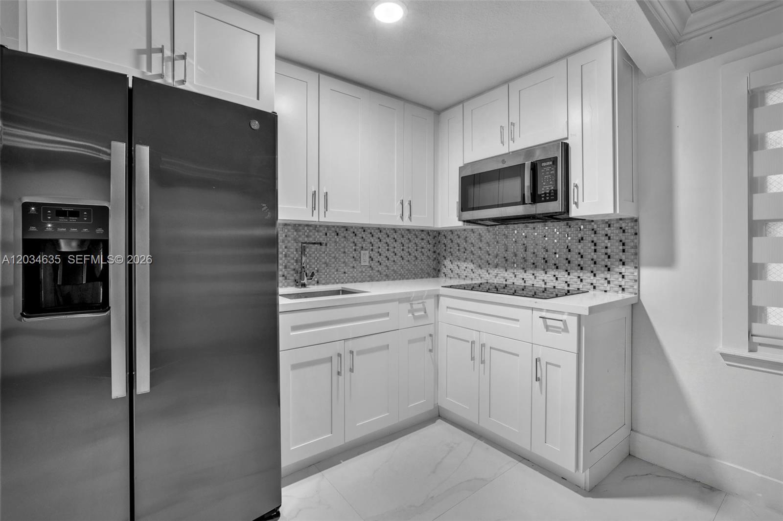 A modern kitchen features white cabinets, stainless steel appliances, and a mosaic tile backsplash — 3245 Virginia St # 16, Miami FL 33133, MIAMI, FL