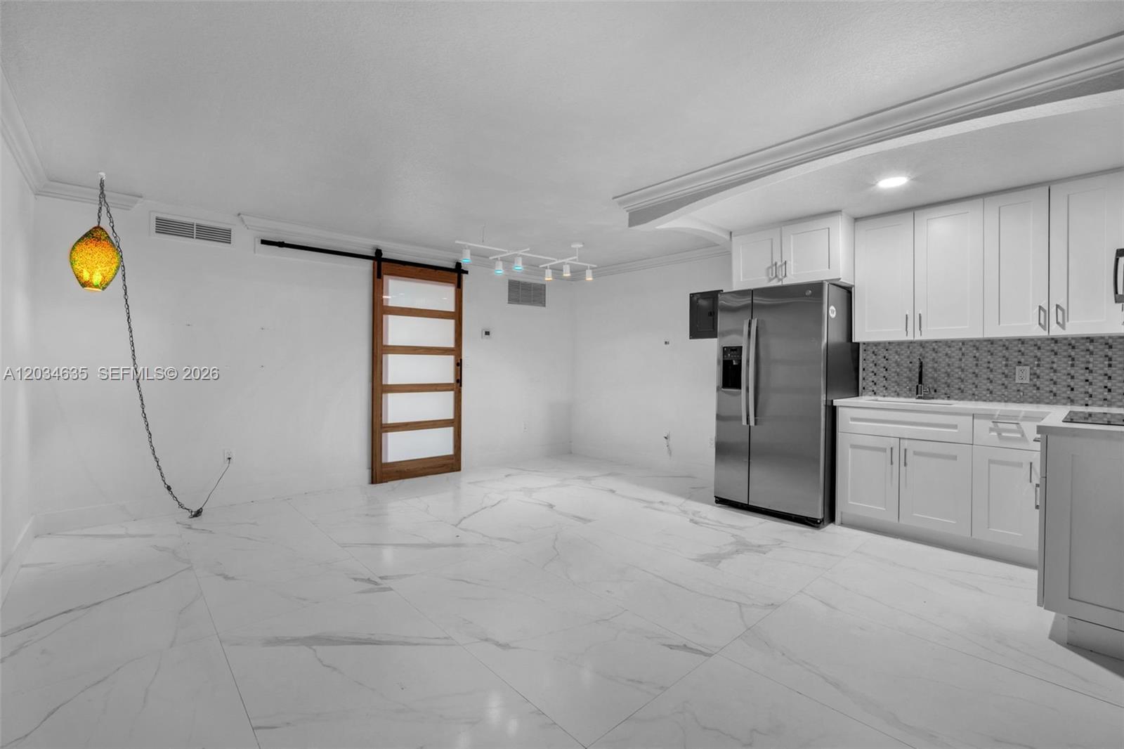 A kitchen and dining area features white cabinets, stainless steel appliances, and marble-look tile flooring — 3245 Virginia St # 16, Miami FL 33133, MIAMI, FL