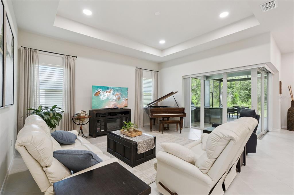 A living room features white leather sofas, a grand piano, and a large sliding glass door — 6524 SHIMMERING SHORES LANE, ST CLOUD, FL