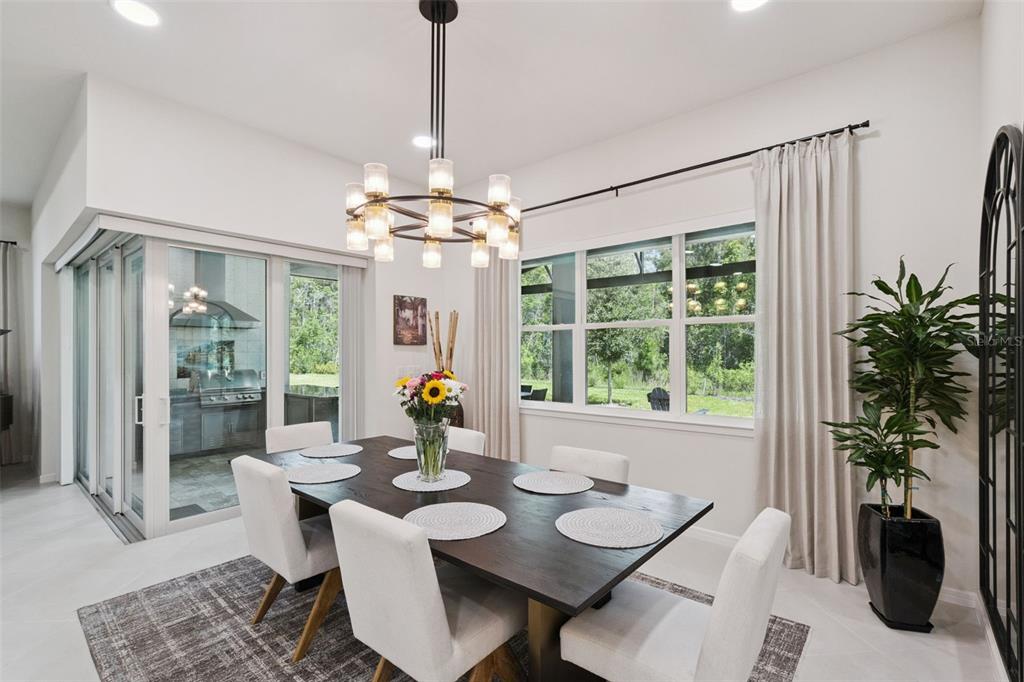 A dining room features a dark wood table, white chairs, a chandelier, and sliding glass doors — 6524 SHIMMERING SHORES LANE, ST CLOUD, FL
