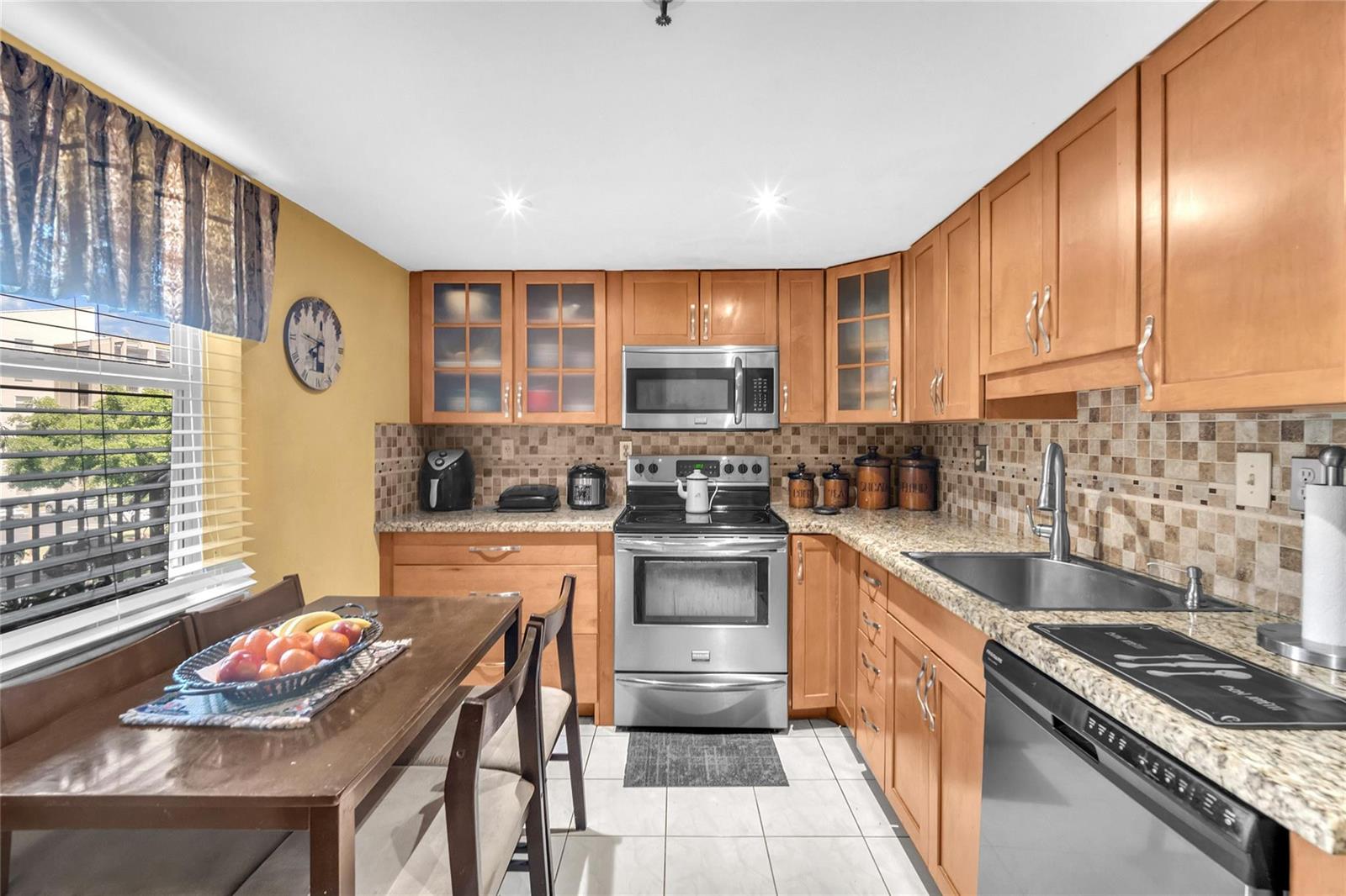 A dining area features a wooden table, chairs, a water cooler, and yellow walls — 3910 Inverrary Boulevard # B, Lauderhill FL 33319, LAUDERHILL, FL