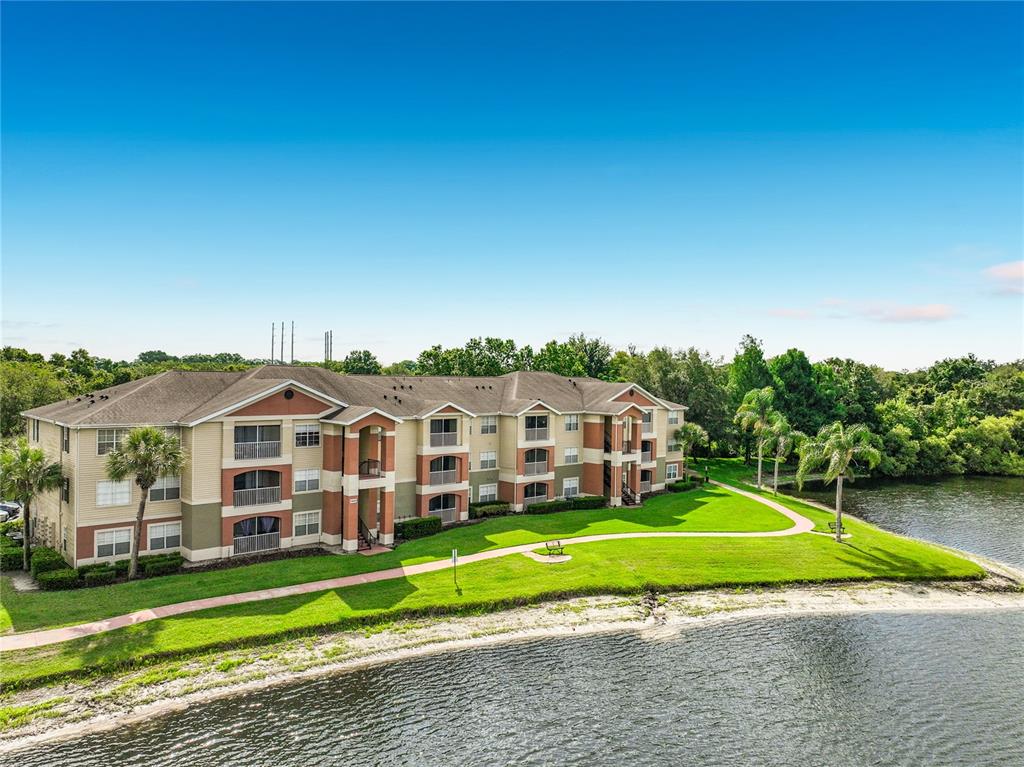 An aerial view of a multi-story apartment building situated next to a lake — 1909 SUMMER CLUB DRIVE UNIT 301, OVIEDO, FL