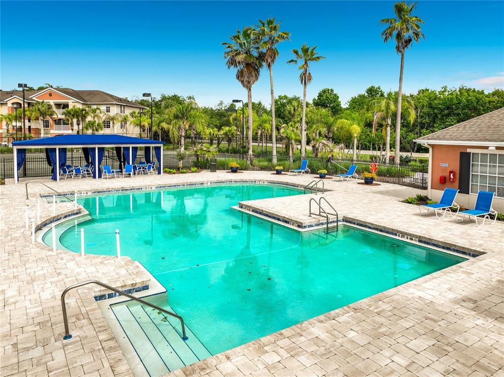 A swimming pool with a blue canopy, lounge chairs, and palm trees on a sunny day — 1909 SUMMER CLUB DRIVE UNIT 301, OVIEDO, FL