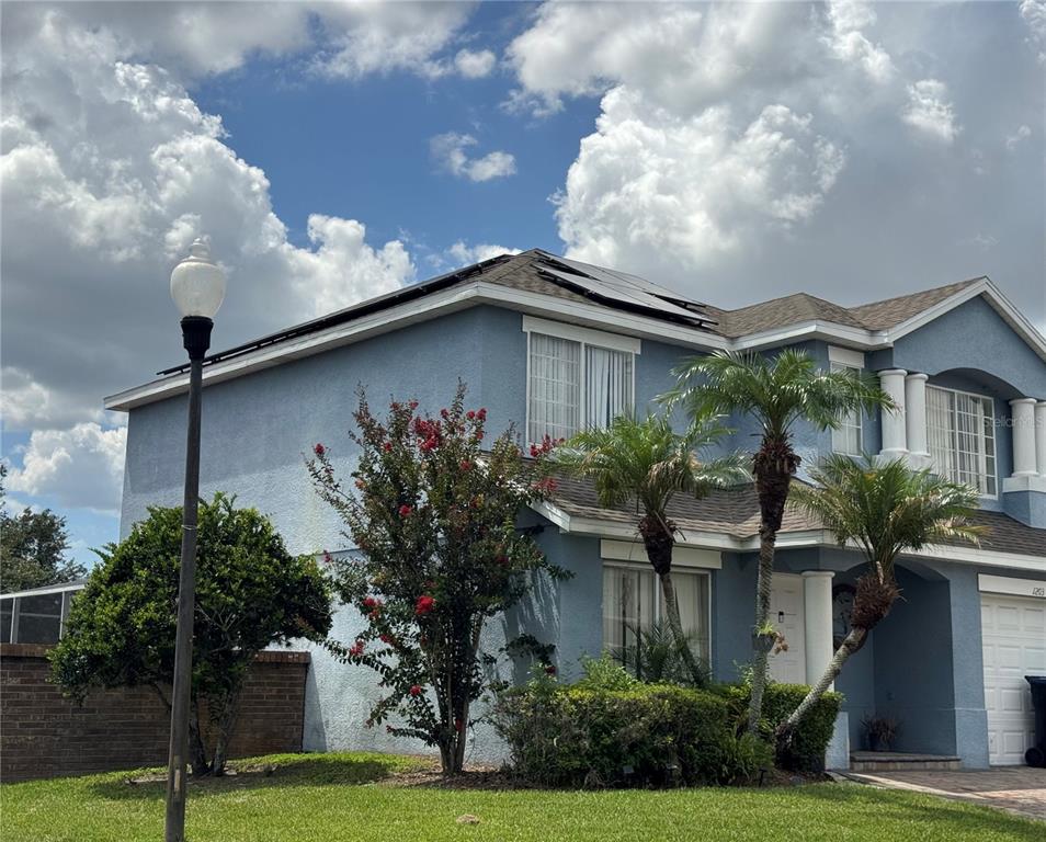 A two-story blue house with solar panels on the roof and a front yard — 1203 SANDESTIN WAY, ORLANDO, FL
