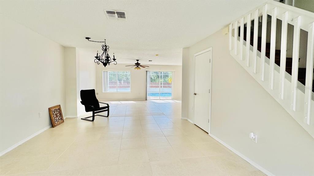 An open-concept living area features tile flooring, a staircase, and sliding glass doors to a pool — 1203 SANDESTIN WAY, ORLANDO, FL