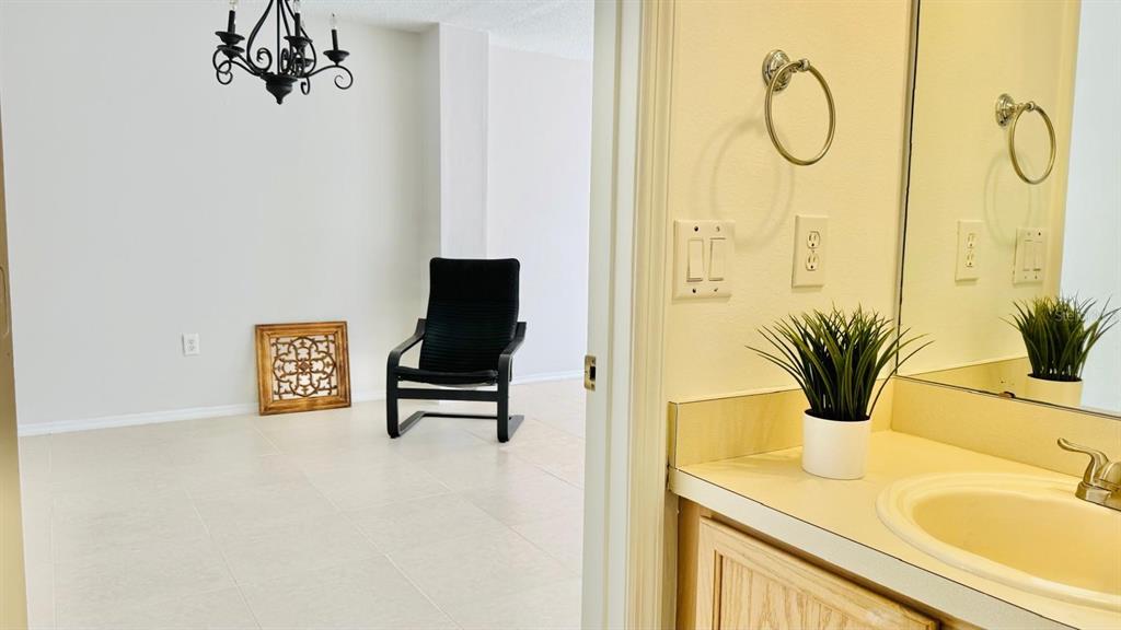 A bathroom vanity with a sink and mirror looks into a room with a chair — 1203 SANDESTIN WAY, ORLANDO, FL