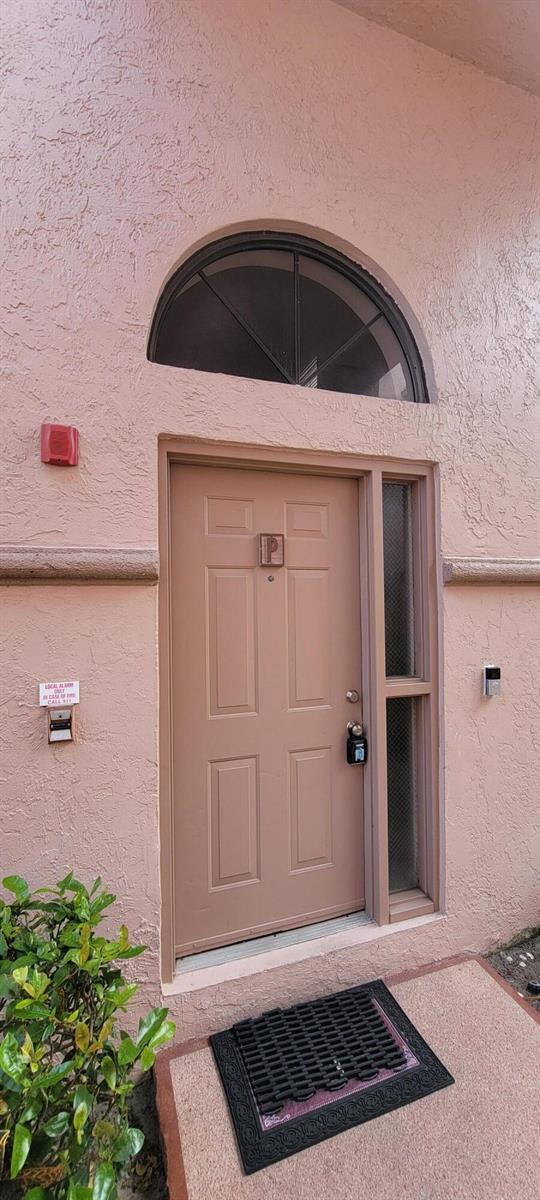 A tan front door with a transom window and a side light on a stucco exterior — 5299 Europa Drive # P, Boynton Beach FL 33437, BOYNTON BEACH, FL