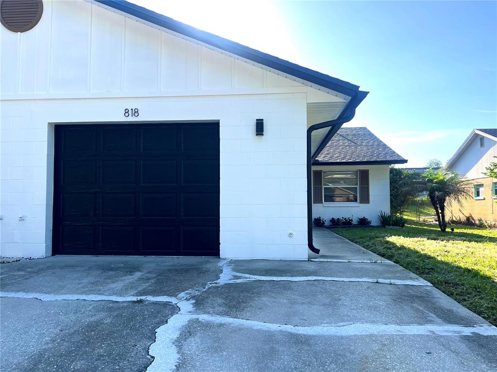 A white concrete block house features a black garage door and a concrete driveway — 816 SLEEPY HARBOUR DRIVE, OCOEE, FL