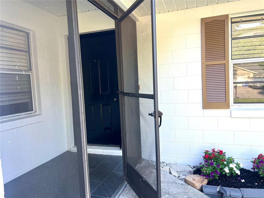 A view of a home entrance with a black front door and a screen door — 816 SLEEPY HARBOUR DRIVE, OCOEE, FL