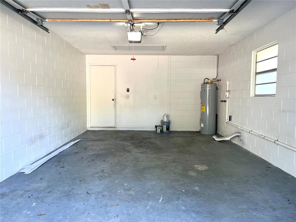 An empty garage with concrete block walls, a water heater, and a single window — 816 SLEEPY HARBOUR DRIVE, OCOEE, FL