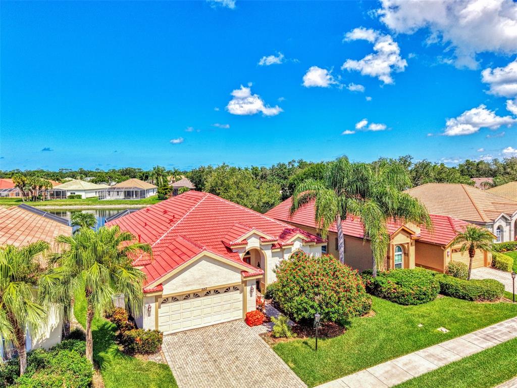 An aerial view shows a single-story house with a red tile roof and a driveway — 5153 HIGHBURY CIRCLE, SARASOTA, FL