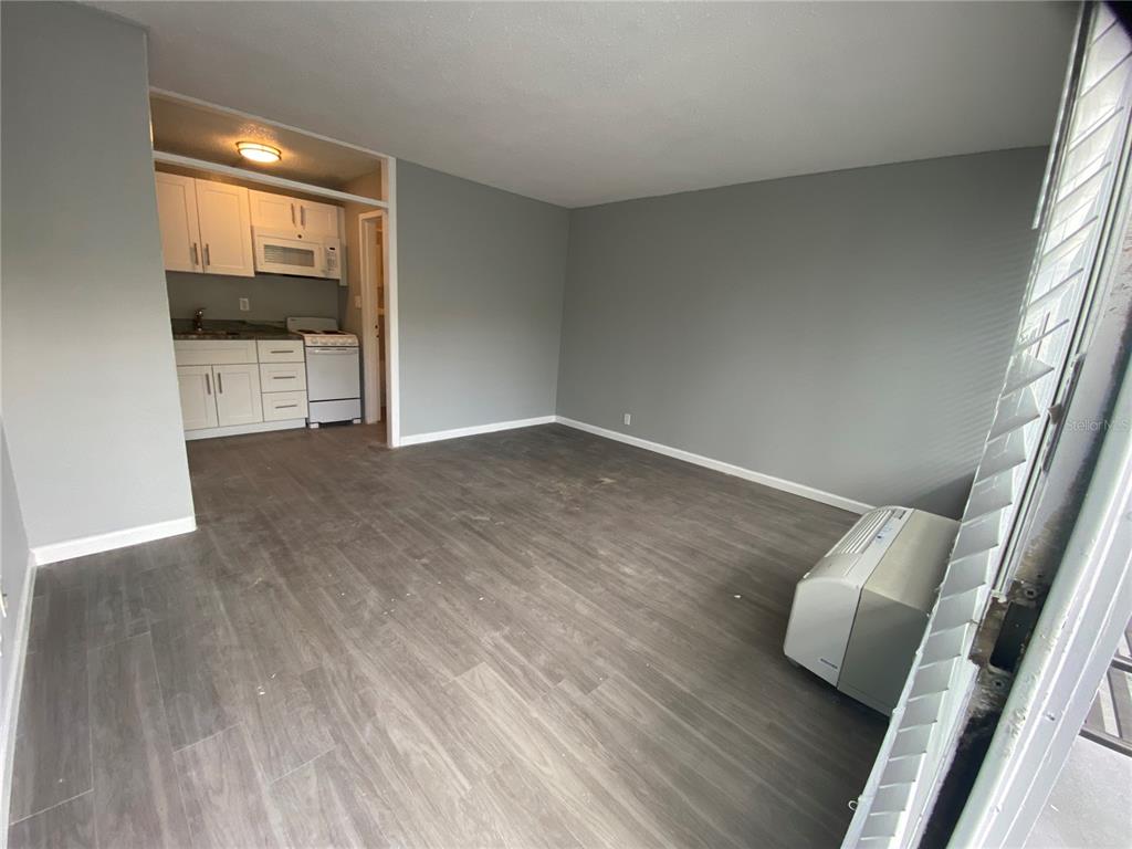 A studio apartment features gray walls, wood-look flooring, a small kitchen, and a wall-mounted AC — 515 BON AIR STREET UNIT 155, LAKELAND, FL