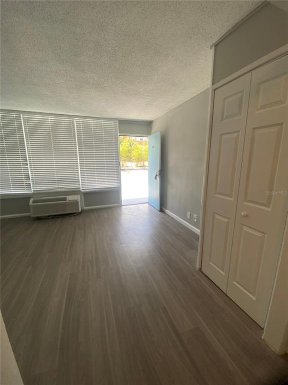 A room with wood-look flooring, a window with blinds, an air conditioner, and a closet — 515 BON AIR STREET UNIT 155, LAKELAND, FL