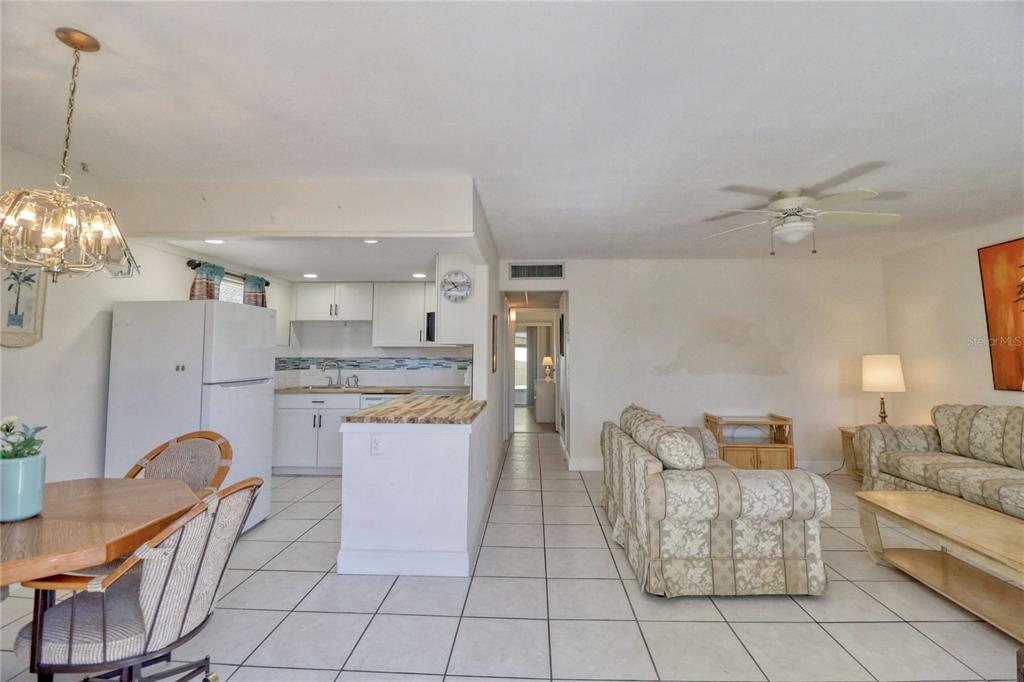 An open-concept living area features a kitchen with white cabinets, tile flooring, and two sofas — 101 CAMBRIDGE TRAIL UNIT 196, SUN CITY CENTER, FL