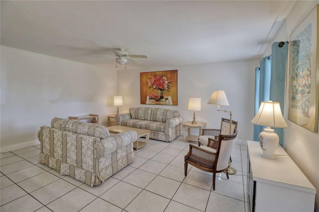 A living room with white tile floors, two patterned sofas, and two accent chairs — 101 CAMBRIDGE TRAIL UNIT 196, SUN CITY CENTER, FL