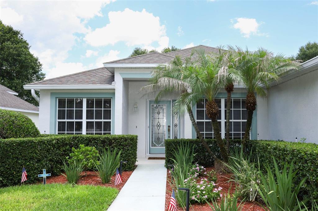 A single-story house with a white exterior, teal trim, and a palm tree in front — 3598 ROLLINGBROOK STREET, CLERMONT, FL
