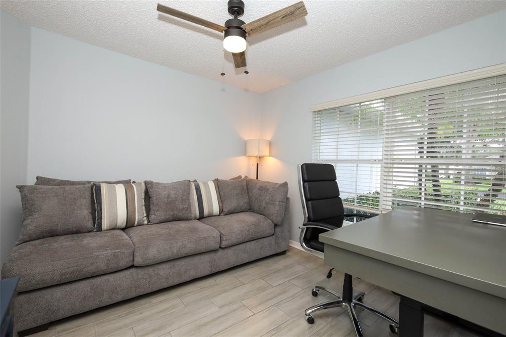 A home office features a gray sofa, a desk with a chair, and a ceiling fan — 3598 ROLLINGBROOK STREET, CLERMONT, FL