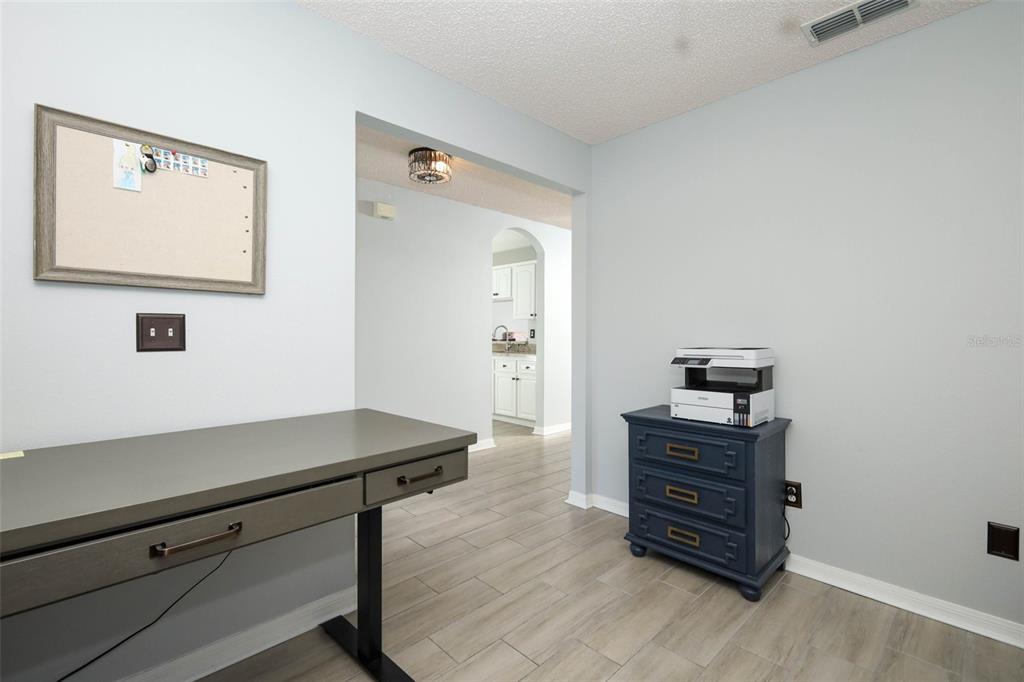 A home office features a gray desk, a blue chest with a printer, and light flooring — 3598 ROLLINGBROOK STREET, CLERMONT, FL