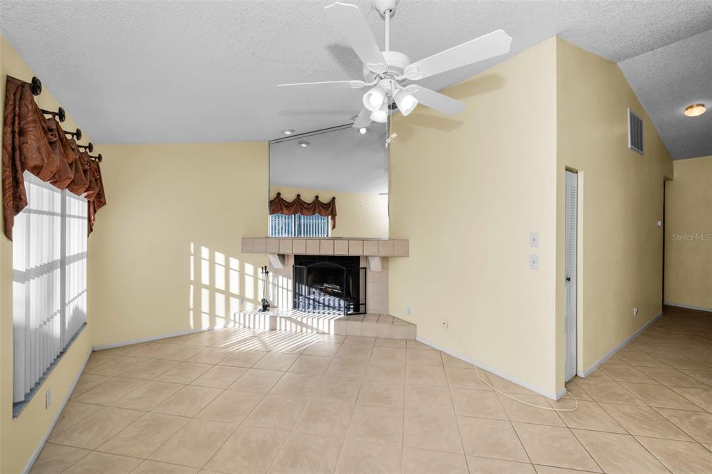 A living room features a corner fireplace, tiled flooring, a ceiling fan, and a mirror — 3500 MAGNOLIA RIDGE CIRCLE UNIT 405, PALM HARBOR, FL