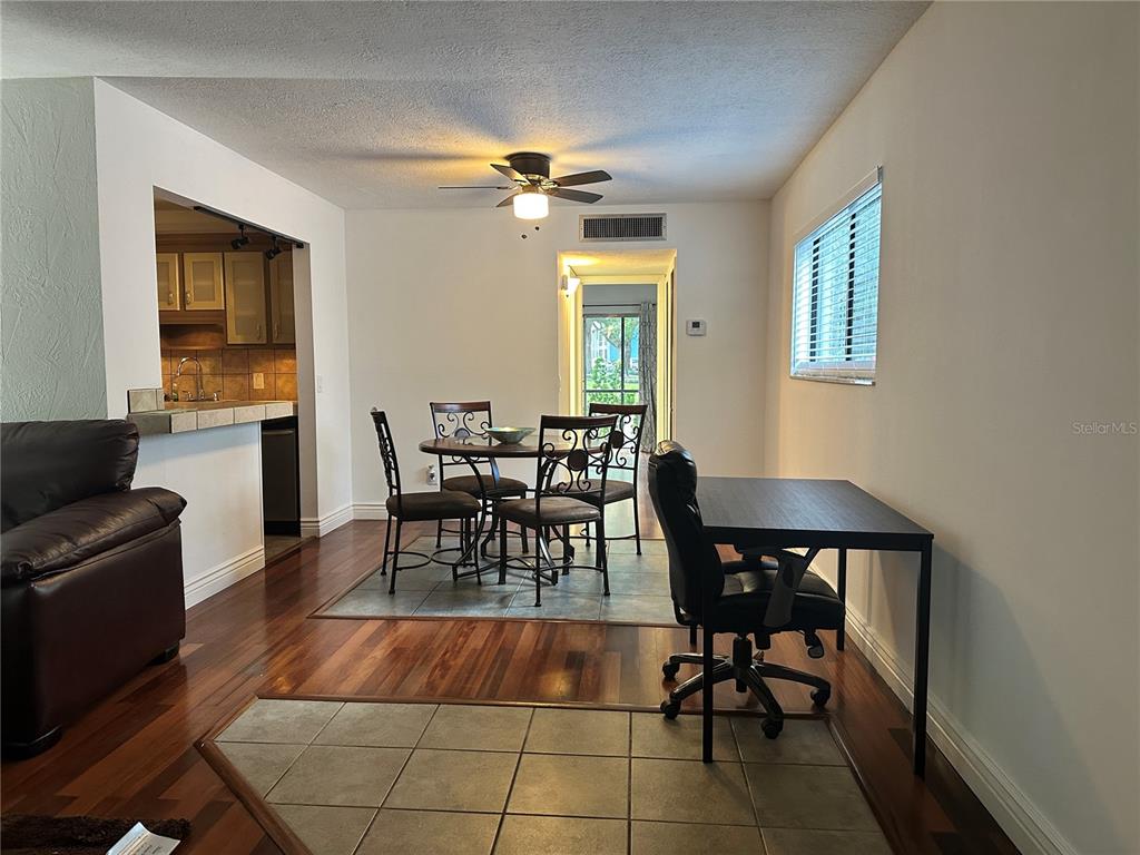A dining area with a table and chairs sits adjacent to a kitchen and desk — 2349 OAK PARK WAY UNIT 107, ORLANDO, FL