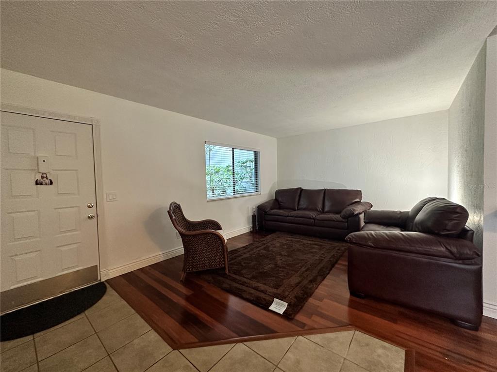 A living room features dark wood flooring, a brown area rug, and leather furniture — 2349 OAK PARK WAY UNIT 107, ORLANDO, FL