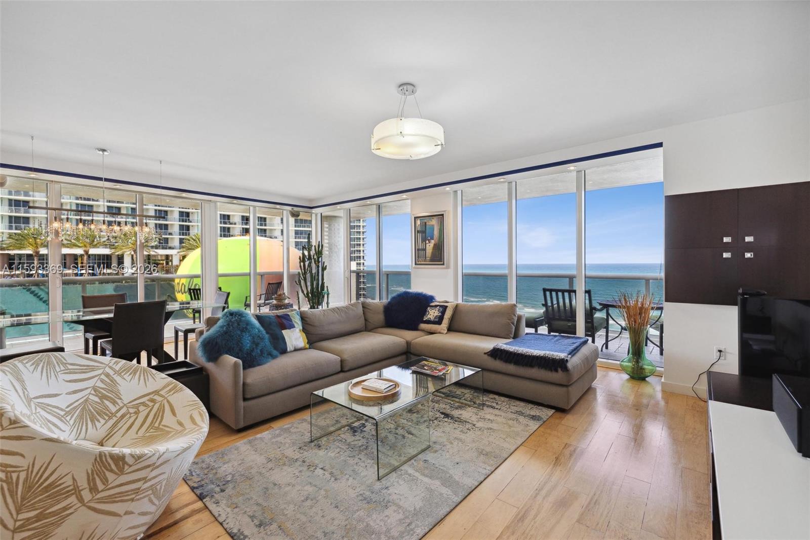 A living room features a sectional sofa, glass coffee table, and floor-to-ceiling windows overlooking the ocean — 1800 S Ocean Dr # 1401, Hallandale Beach FL 33009, HALLANDALE BEACH, FL