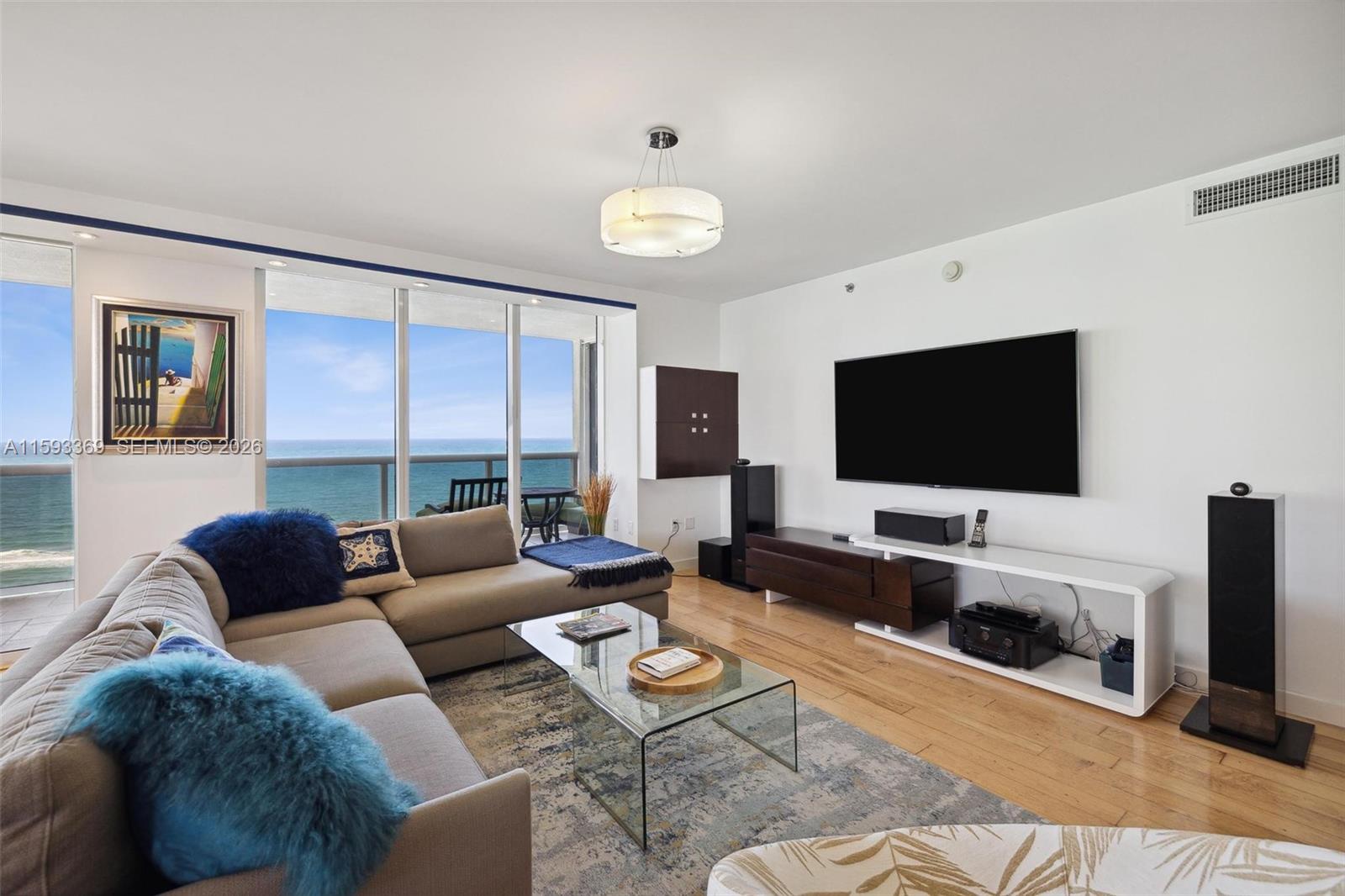 A living room features a sectional sofa, glass coffee table, and ocean view balcony — 1800 S Ocean Dr # 1401, Hallandale Beach FL 33009, HALLANDALE BEACH, FL