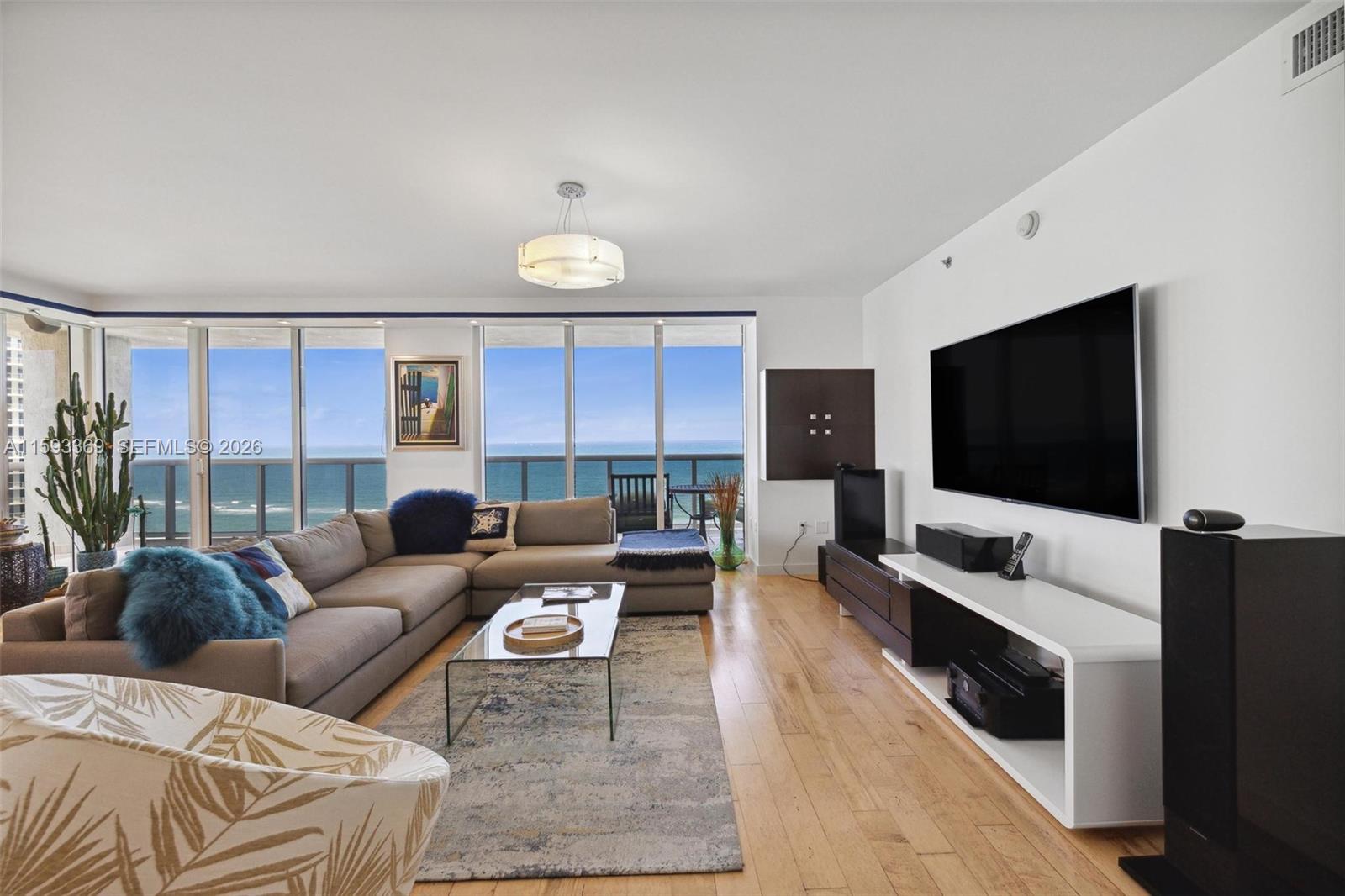 A living room features a sectional sofa, a glass coffee table, and ocean views — 1800 S Ocean Dr # 1401, Hallandale Beach FL 33009, HALLANDALE BEACH, FL