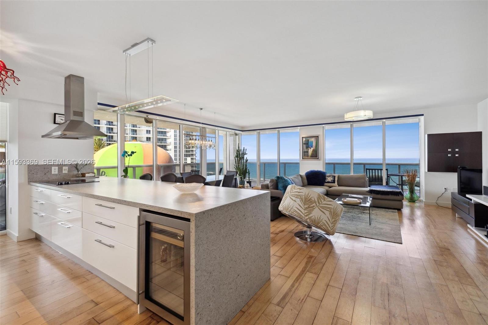 An open-concept kitchen and living area features white cabinetry, a stone island, and ocean views — 1800 S Ocean Dr # 1401, Hallandale Beach FL 33009, HALLANDALE BEACH, FL