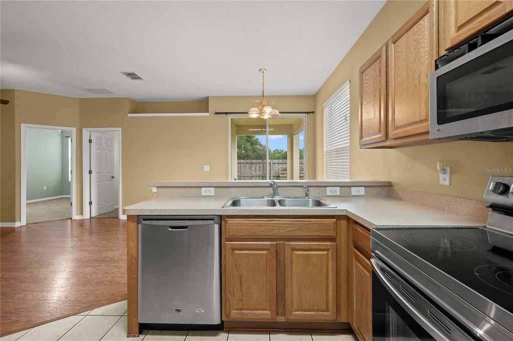 A kitchen with oak cabinets, stainless steel appliances, and a view of the backyard — 2556 SE 75TH BOULEVARD, BUSHNELL, FL