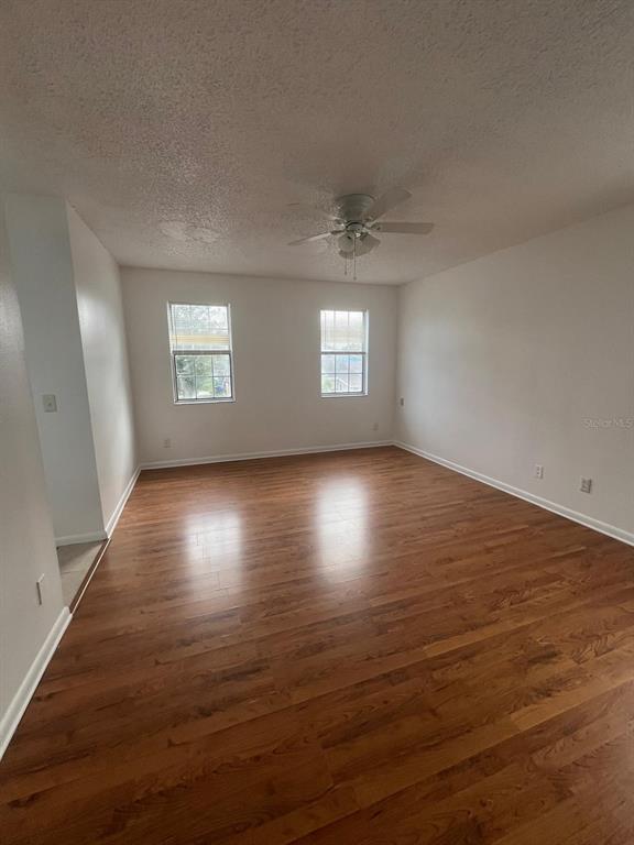 An empty room features wood-look flooring, white walls, two windows, and a ceiling fan — 11001 SPRINGRIDGE DRIVE, TAMPA, FL