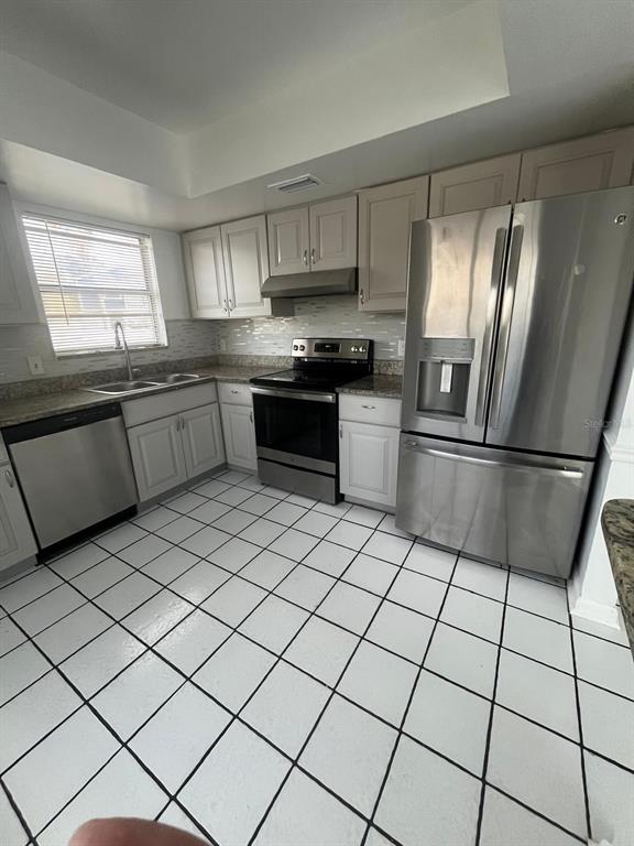 A kitchen with white cabinets, stainless steel appliances, granite countertops, and white tiled flooring — 11001 SPRINGRIDGE DRIVE, TAMPA, FL