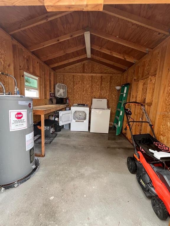 A wooden shed interior contains a water heater, a washer, a dryer, and a lawnmower — 11001 SPRINGRIDGE DRIVE, TAMPA, FL