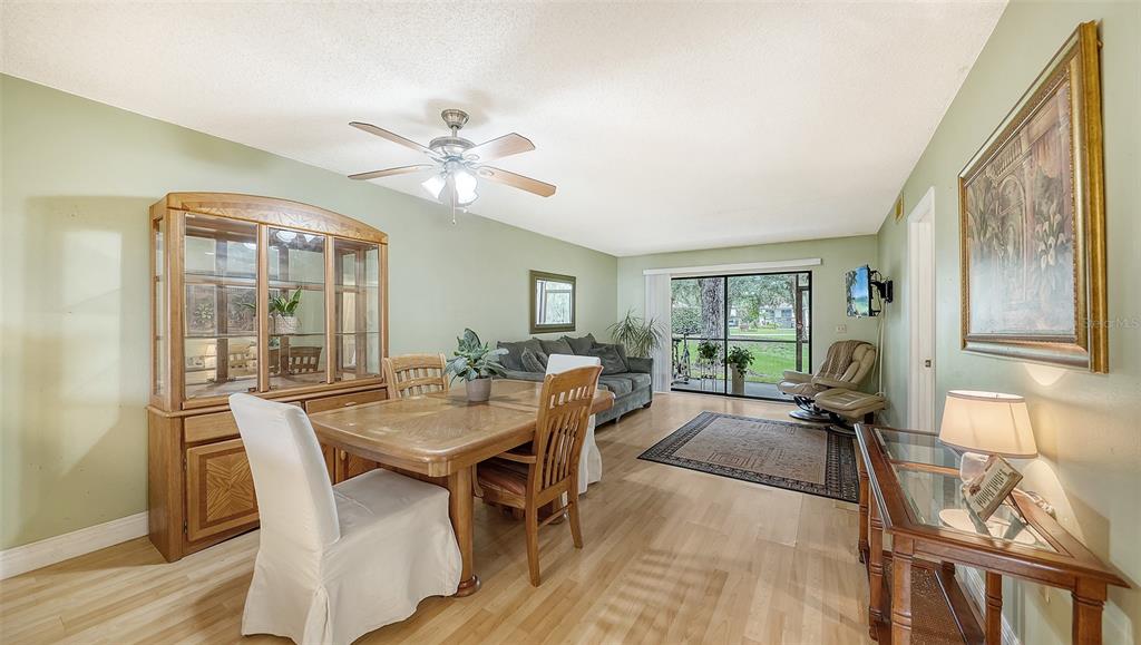 A dining and living area with light wood floors, a ceiling fan, and sliding glass doors — 7864 EAGLE CREEK DRIVE UNIT 7864, SARASOTA, FL