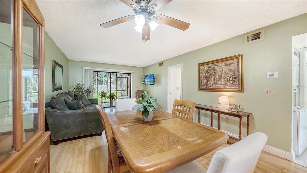 A dining area with a wooden table and chairs sits adjacent to a living room — 7864 EAGLE CREEK DRIVE UNIT 7864, SARASOTA, FL