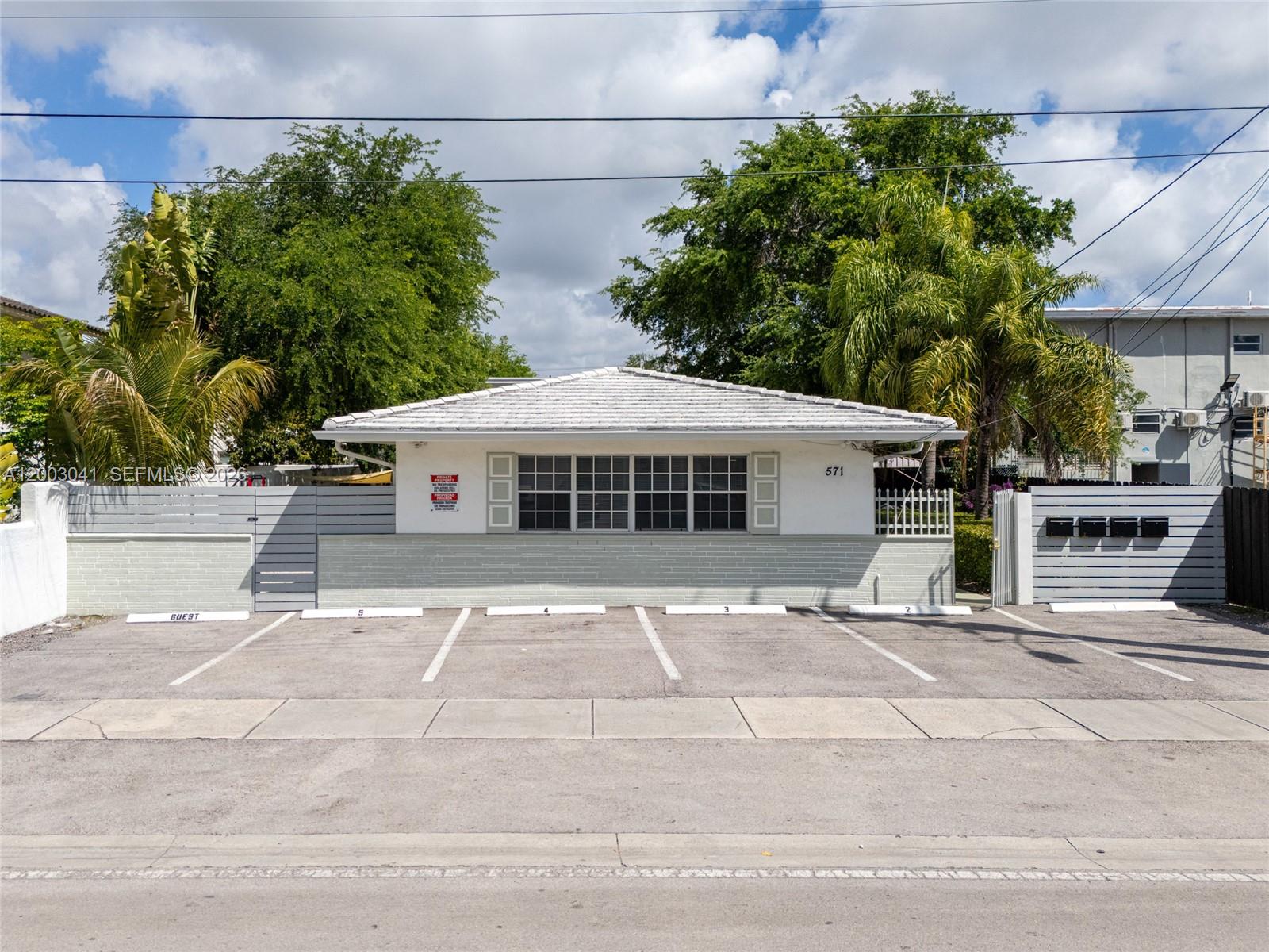 A single-story building with a white tiled roof and five numbered parking spaces in front — 571 NE 67th St, Miami FL 33138, MIAMI, FL