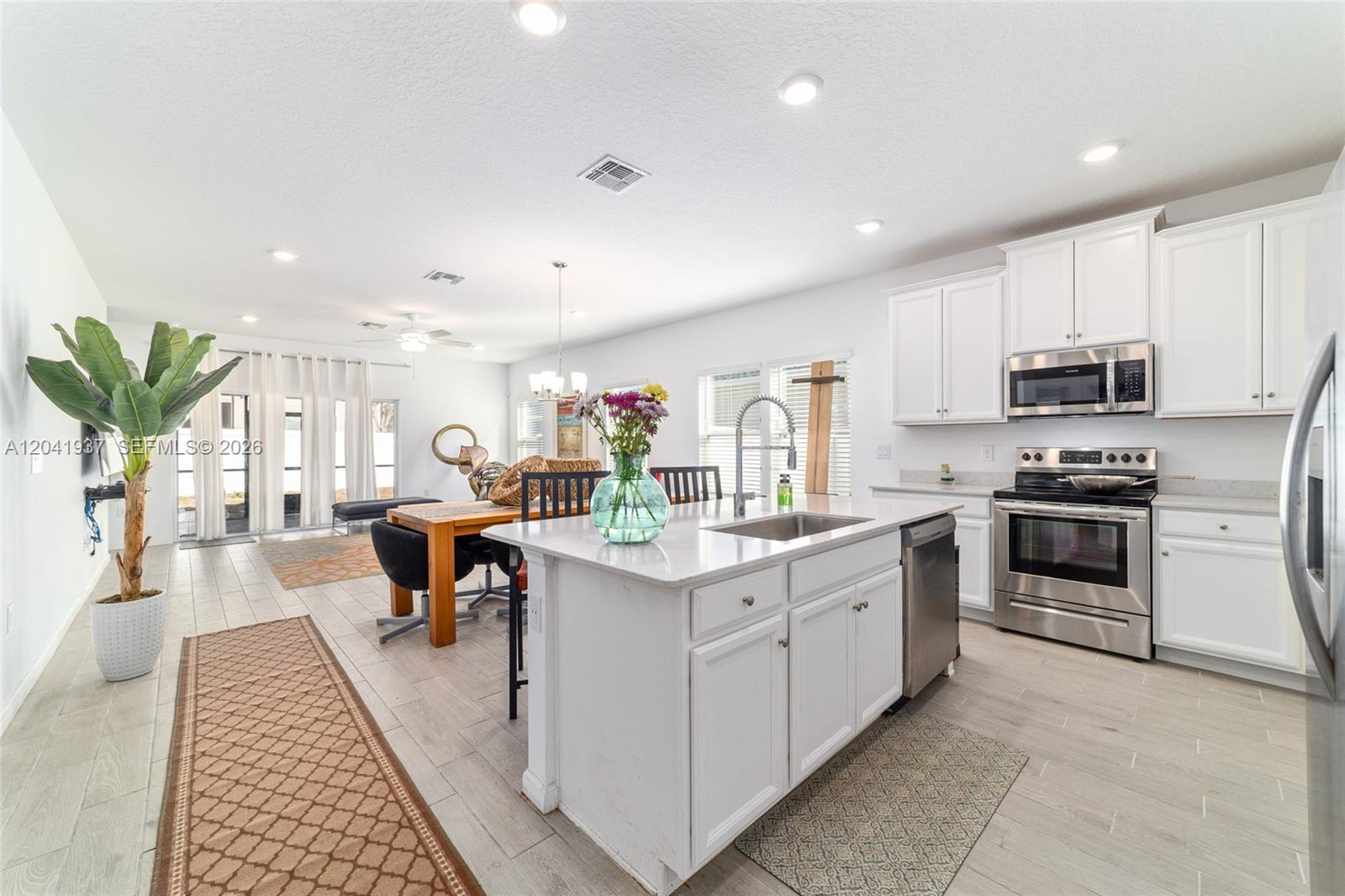 A kitchen with white cabinets and a central island flows into a dining area — 7451 SW 76TH TER, Ocala FL 34481, OCALA, FL