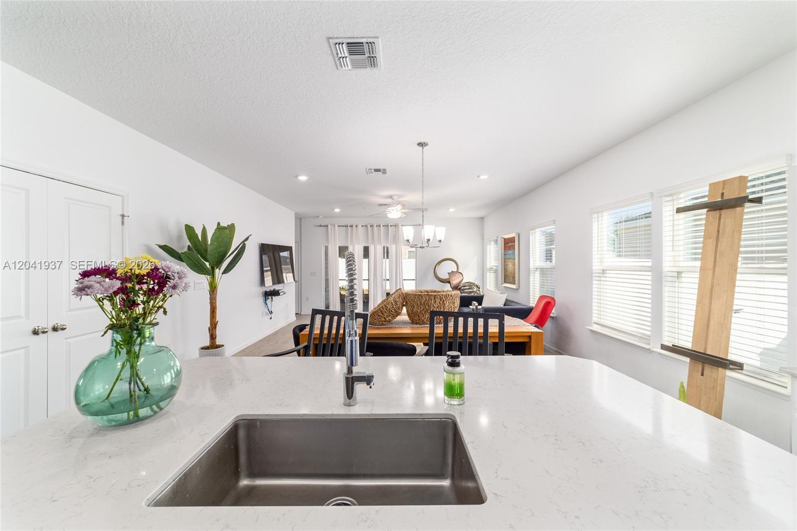 A kitchen island with a stainless steel sink overlooks an open-concept dining and living area — 7451 SW 76TH TER, Ocala FL 34481, OCALA, FL