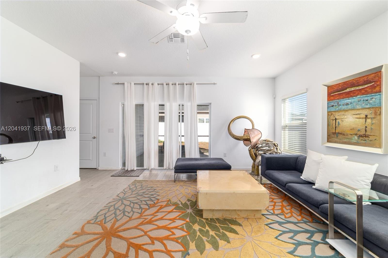 A living room features a blue sofa, a patterned rug, and a large metal sculpture — 7451 SW 76TH TER, Ocala FL 34481, OCALA, FL